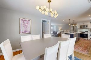 a kitchen and dining room with a table and white chairs at Champagne Dreams in Dennis