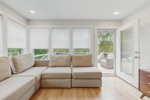 a living room with a couch and windows at The Saffron Cottage in Wellfleet