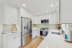 a kitchen with white cabinets and a stainless steel refrigerator at The Saffron Cottage in Wellfleet +7 photos