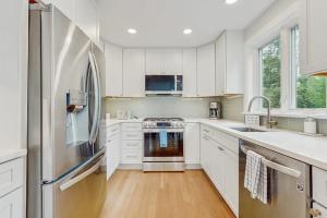 a kitchen with white cabinets and a stainless steel refrigerator at The Saffron Cottage in Wellfleet