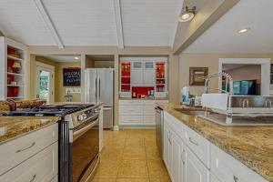 a large kitchen with a sink and a refrigerator at Sanctuary In The Woods in East Falmouth +16 photos
