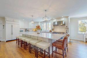 a kitchen with a large white island with bar chairs at Plum Paradise in Barnstable +38 photos