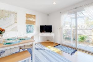 a white living room with a table and a television at Modern Beach & Town Getaway in Falmouth