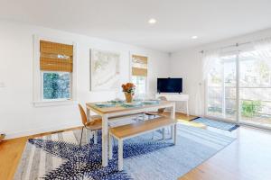 a white living room with a table and a tv at Modern Beach & Town Getaway in Falmouth
