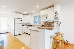 a kitchen with white cabinets and a white refrigerator at Modern Beach & Town Getaway in Falmouth