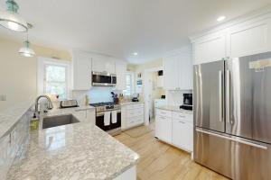 a kitchen with white cabinets and a stainless steel refrigerator at Set Sail in Oak Bluffs +24 photos