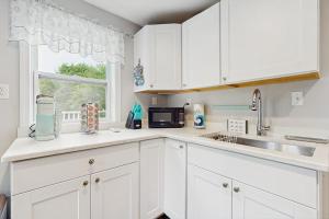a kitchen with white cabinets and a sink and a window at Garage Suite in Oak Bluffs