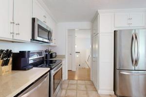 a kitchen with white cabinets and a stainless steel refrigerator at Seabreeze in Dennis Port +35 photos