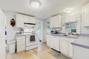 a white kitchen with white cabinets and a sink at Gingerbread Dream in Oak Bluffs