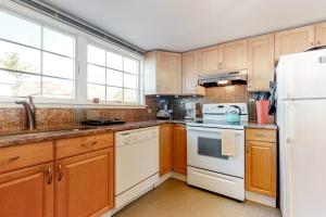 a kitchen with wooden cabinets and white appliances at Cape Point Escape in Provincetown +16 photos