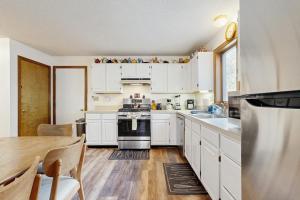 a kitchen with white cabinets and a wooden table at Fallen Oak Retreat in Oak Bluffs