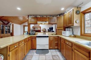 a kitchen with wooden cabinets and a white stove top oven at C-Haven in West Tisbury +16 photos