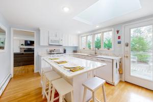 a kitchen with white cabinets and a large island with stools at Saltwater Haven in Orleans