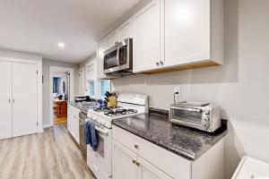 a kitchen with white cabinets and a stove top oven at Seabreeze Escape in Barnstable +21 photos