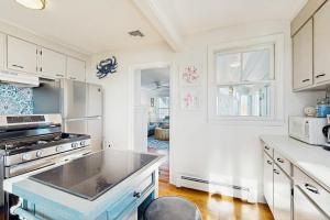 a kitchen with white cabinets and a stove top oven at SEA-esta in Falmouth