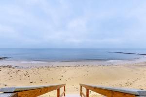 a wooden bench sitting on a beach with the ocean at Immaculate Beach Condo in Dennis Port