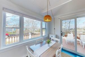a dining room with a table and chairs and windows at Cottage by the Bay in Pocasset