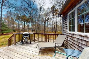 a porch with a grill and a chair on a house at The Tranquil Heron Cottage in Eastham