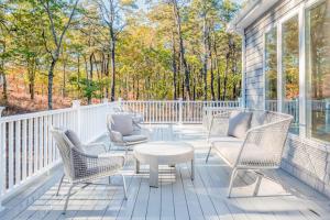 a screened porch with chairs and a table at Peace Among the Pines in Wellfleet
