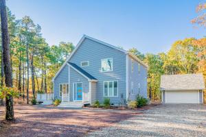 a blue house with a garage in the woods at Peace Among the Pines in Wellfleet