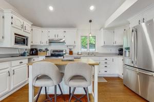 a kitchen with white cabinets and a table and two chairs at Strawberry Hill Haven in Hyannis +17 photos