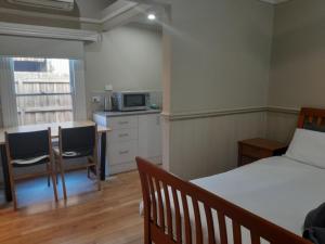 a bedroom with a bed and a kitchen with a microwave at Seymour Studios in Seymour +18 photos