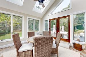a dining room with a table and chairs and windows at Bird's Paradise in Oak Bluffs