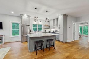 a kitchen with a large island with two bar stools at Heritage Escape in Mashpee