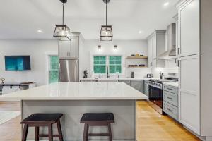 a large white kitchen with a large island with two bar stools at Heritage Escape in Mashpee +16 photos