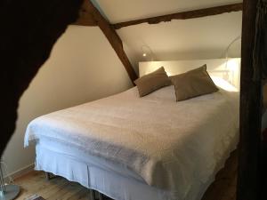 a bedroom with a white bed with two pillows at Studio des Perriots in Englesqueville-la-Percée +25 photos