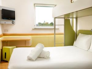 a hotel room with a bed with a towel on it at ibis budget Sheffield Arena in Sheffield