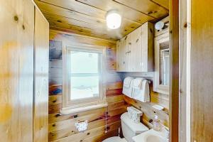 a bathroom with wooden walls and a toilet and a window at Dune Grass Shores in Beulah +13 photos