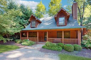a wooden house with a porch and some bushes at Kingfisher Cove Cabin 19 in Saugatuck