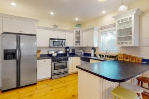 a kitchen with a stainless steel refrigerator and white cabinets at Green Glen in Empire +15 photos