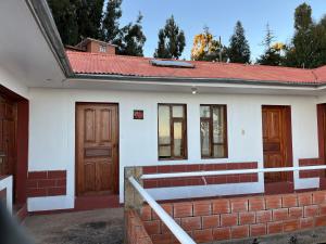 a white house with a red roof and two doors at Qocha Simi Homestay in Ocosuyo