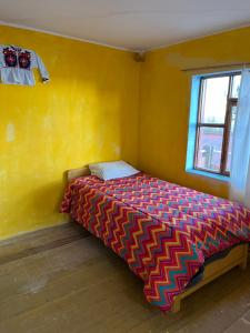a bedroom with a bed in a yellow wall at Qocha Simi Homestay in Ocosuyo