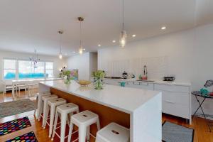 a kitchen with a large white counter and stools at Downtown Hideaway in New Buffalo +19 photos