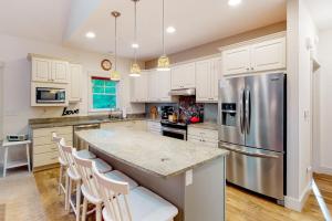a kitchen with white cabinets and a stainless steel refrigerator at Cardinal Corner in Glen Arbor +17 photos