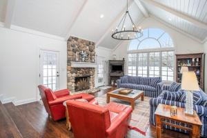 a living room with couches and a stone fireplace at Point Cottage at Point O' Woods in Benton Harbor