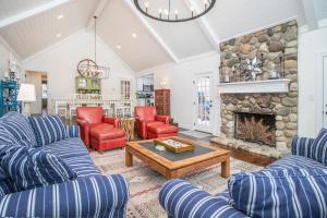 a living room with couches and a stone fireplace at Point Cottage at Point O' Woods in Benton Harbor