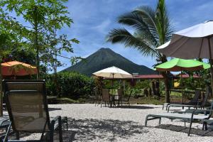 een groep stoelen en parasols met een berg op de achtergrond bij Hotel Roca Negra Del Arenal in Fortuna