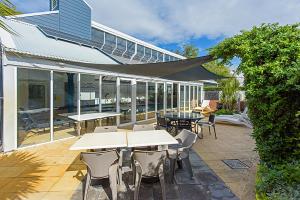 a patio with tables and chairs and a building at Abby’s Beach Villa in Broadwater