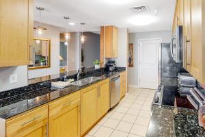 a large kitchen with wooden cabinets and black counter tops at The Sanctuary - Summer Breeze A114 in Virginia Beach
