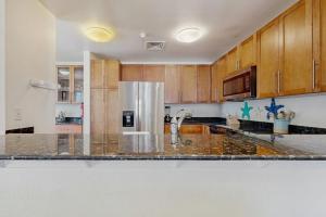 a kitchen with wooden cabinets and a stainless steel refrigerator at The Sanctuary - Blue Lagoon A323 in Virginia Beach +20 photos