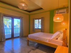 a bedroom with a bed with green walls and a window at Kapunoan Beach House in Burgos