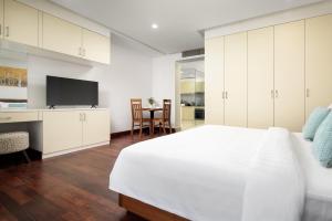 a white bedroom with a large bed and a tv at Angkor Mansion & Apartment in Siem Reap