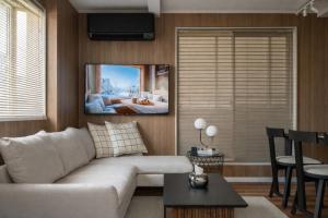 a living room with a couch and a tv on the wall at The Ichikawa House in Ichikawa