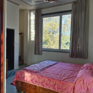 a bedroom with a bed and a large window at Thano Retreat in Dehradun
