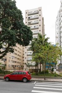 een rode auto geparkeerd op een straat met gebouwen bij Apartamento Floripa in Florianópolis