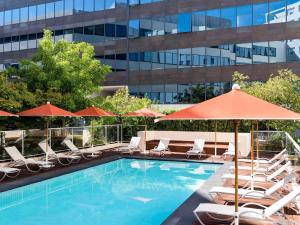 a pool with chairs and umbrellas next to a building at Novotel Suites Nice Airport in Nice